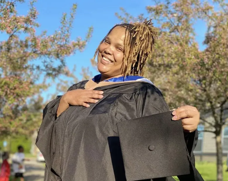 woman smiling outside with a cap and gown
