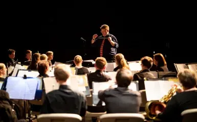 Band students playing instruments with conductor in front
