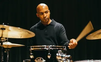 An image of drummer Adonis Rose playing on a drum kit.