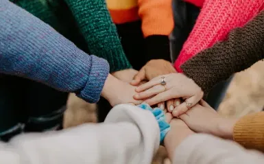 group of people standing in circle with their hands in the center